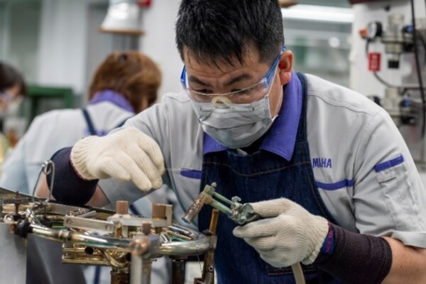 Um artesão soldando peças metálicas com solda sem chumbo.