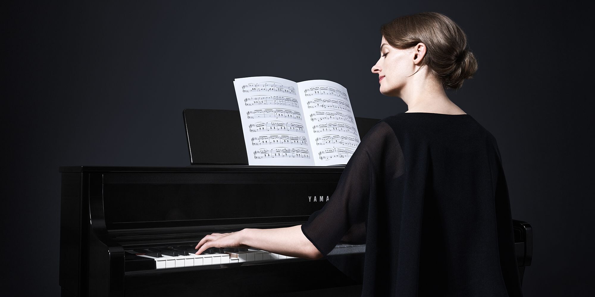 A person who plays Yamaha Clavinova CLP-875PE while looking at sheet music