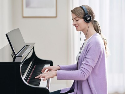 A person playing Yamaha Clavinova CLP-875PE with headphones on