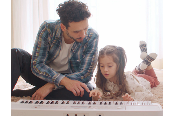 Daughter playing the EZ-310 and father watching on the floor
