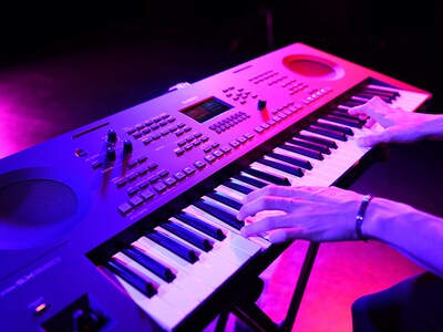 Close-up de mãos tocando um teclado durante uma apresentação ao vivo.