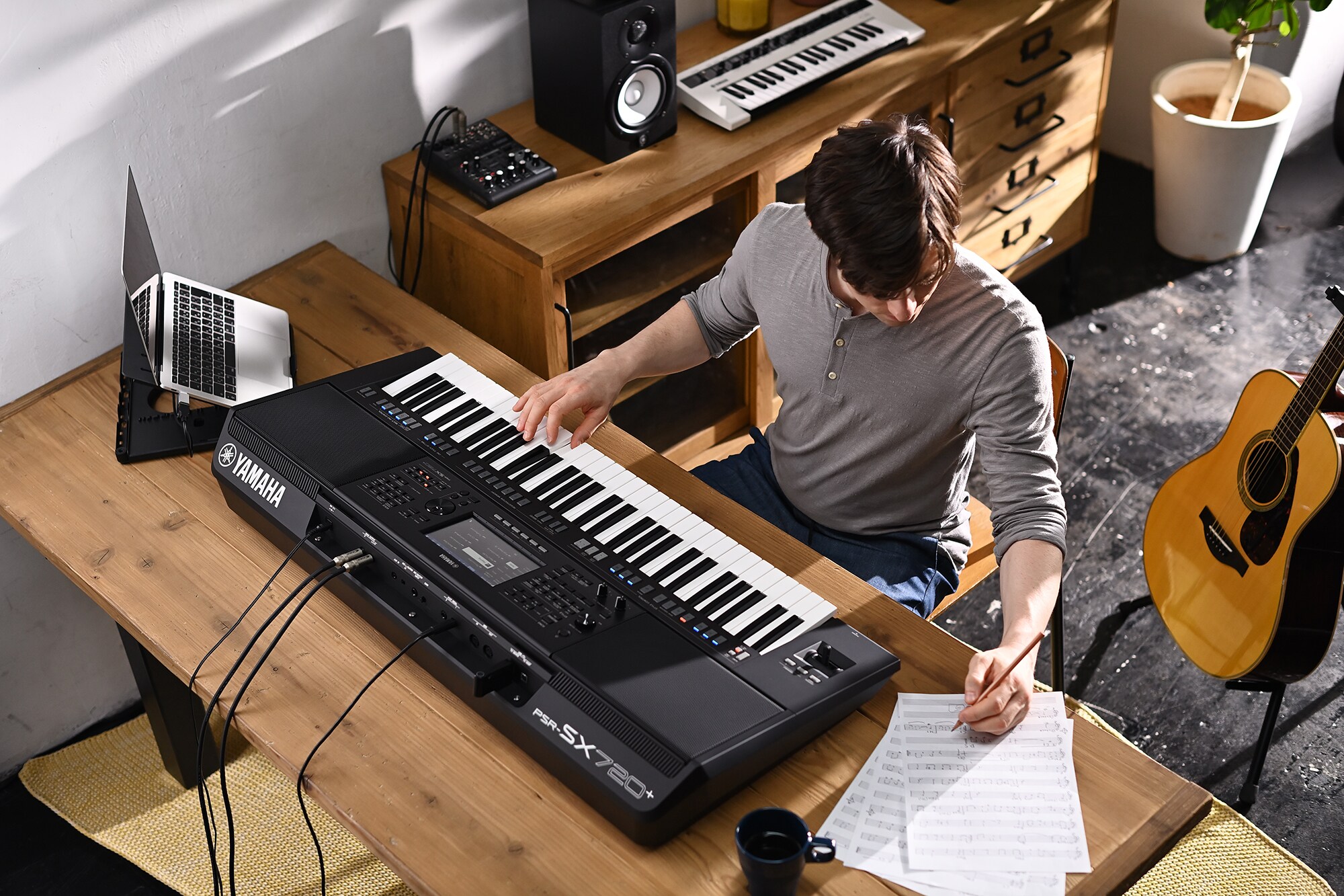 Foto de uma pessoa escrevendo em uma partitura enquanto toca o Arranjador Workstation Yamaha PSR-SX720+