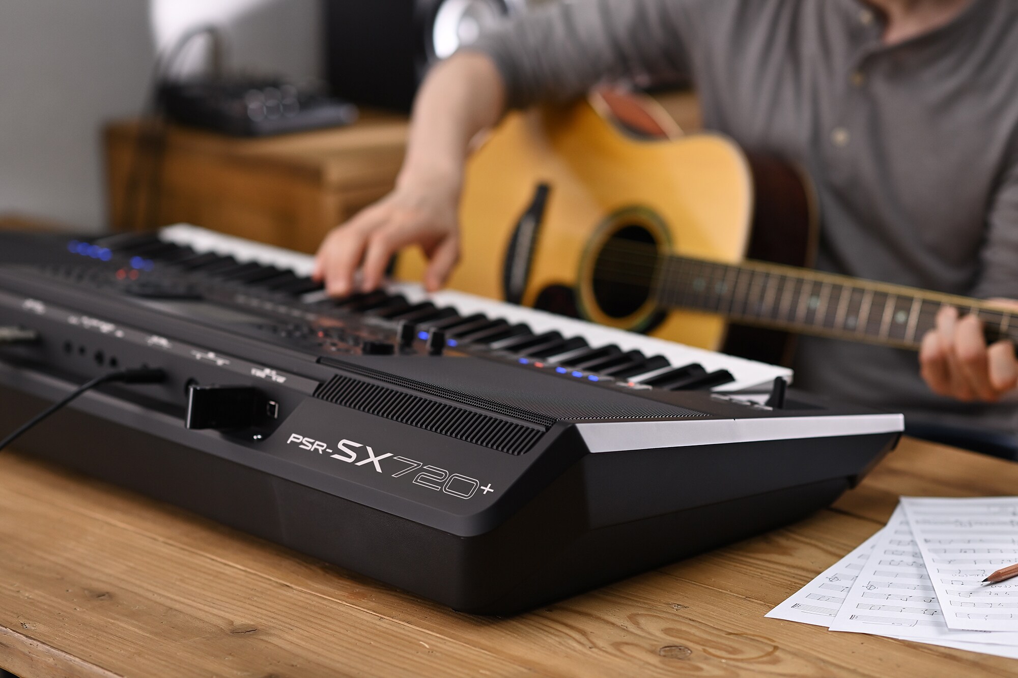Foto de uma pessoa tocando a Arranjador Workstation Yamaha PSR-SX720+ enquanto segura um violão