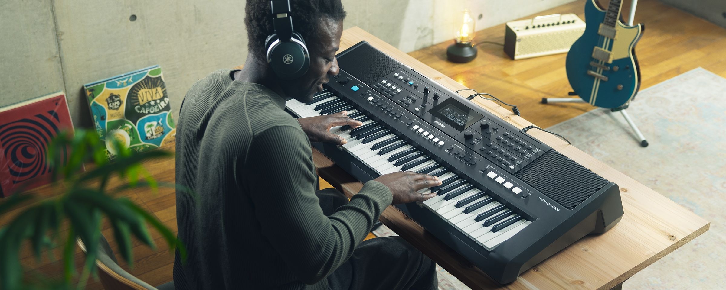 Uma pessoa tocando o Teclado Portátil Yamaha PSR-E483 com fones de ouvido