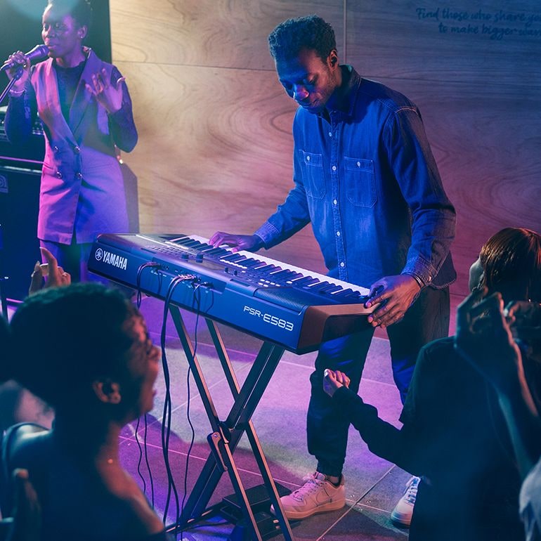 Uma pessoa tocando o Teclado Portátil Yamaha PSR-E583 no palco