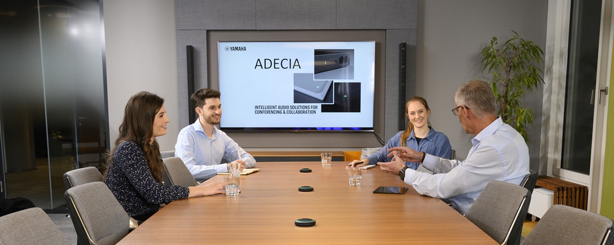 Cena de reunião mostrando a solução de microfones de mesa que proporciona som nítido para videoconferências no escritório