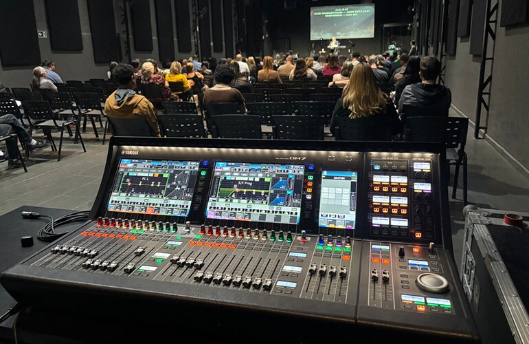 Centro de treinamento de São Paulo, com consoles de mixagem digital e participantes em uma sala de treinamento de áudio profissional.