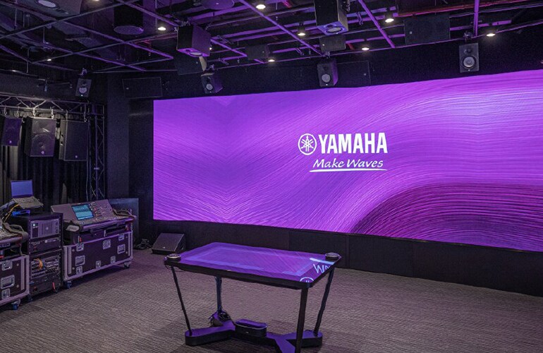 Centro de treinamento de Bangkok, com video wall da Yamaha, área de palco e equipamentos de áudio profissional.