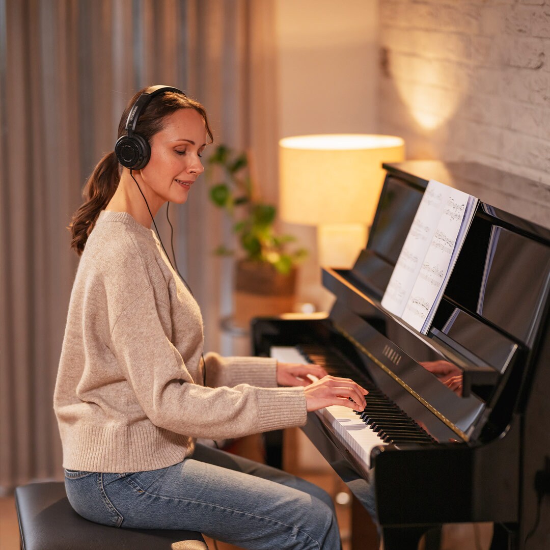 Uma mulher se diverte tocando piano usando fones de ouvido