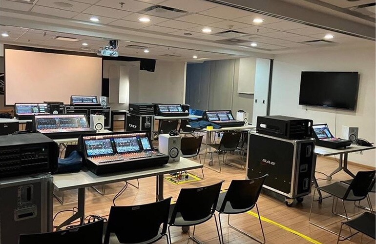 Centro de treinamento da Cidade do México, com consoles de mixagem digital, telas e assentos na sala de treinamento.