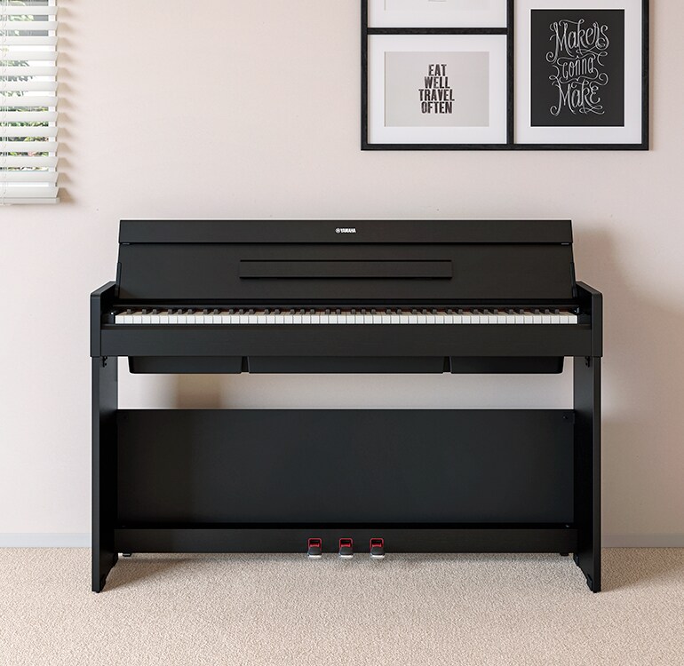 Uma sala de estar com um piano ARIUS preto posicionado ao lado de prateleiras de parede com luminárias e um difusor, harmoniosamente integrado ao ambiente.