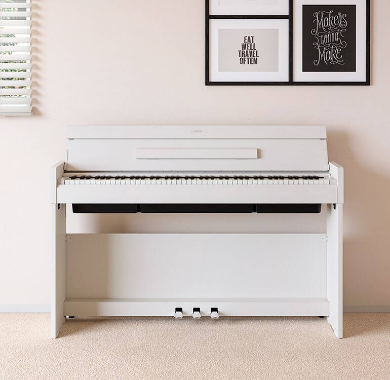 Uma sala de estar com um piano ARIUS branco posicionado ao lado de prateleiras de parede com luminárias e um difusor, harmoniosamente integrado ao ambiente.