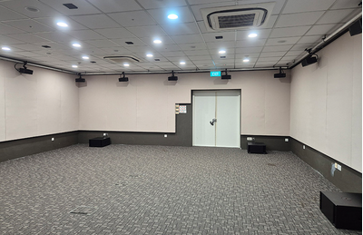 Sala do centro de treinamento de Singapura, com assentos, tela de apresentação e equipamentos de áudio.
