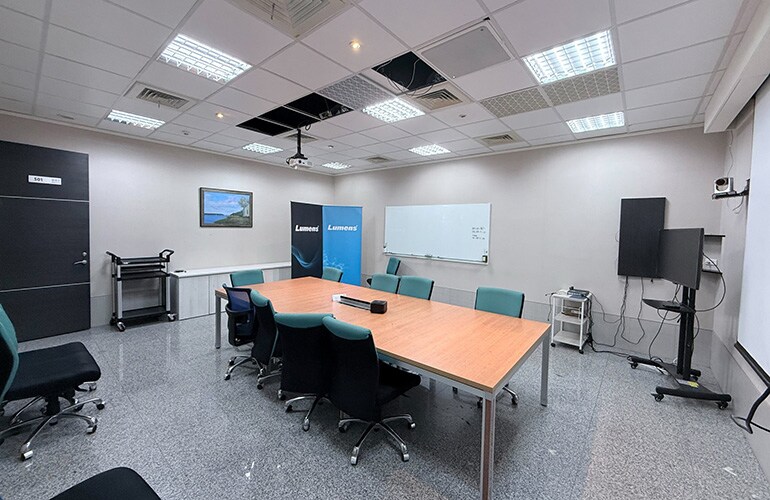 Centro de treinamento da Cidade de Hsinchu, com mesa de reunião, tela de exibição e equipamentos de apresentação.