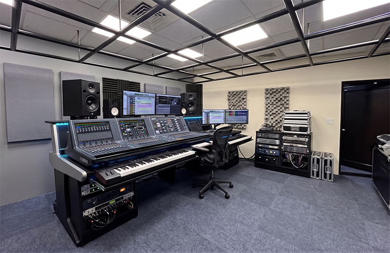 Centro de treinamento de Nova Taipé, com console de mixagem digital, caixas acústicas e tela de apresentação.