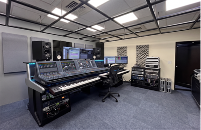 Centro de treinamento de Nova Taipé, com console de mixagem digital, caixas acústicas e tela de apresentação.