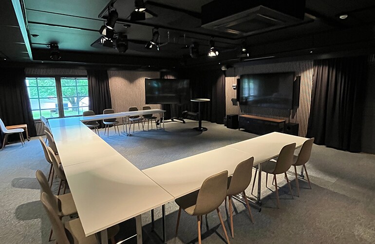 Centro de treinamento de Gotemburgo, com uma grande mesa de conferência, caixas acústicas de teto e sistema de apresentação.