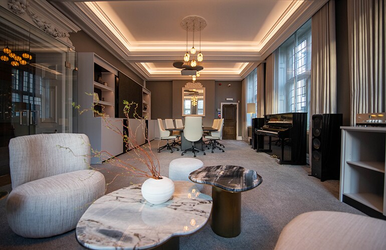 Sala em estilo lounge do centro de treinamento de Londres, com assentos e área de apresentação.