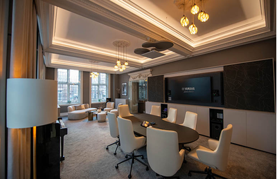 Sala de reunião do centro de treinamento de Londres, com mesas, assentos e tela de exibição.