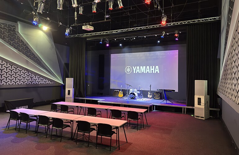 Auditório do centro de treinamento de Joanesburgo, com tela de exibição Yamaha, área de palco e assentos.