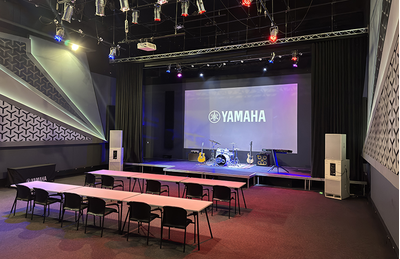 Auditório do centro de treinamento de Joanesburgo, com tela de exibição Yamaha, área de palco e assentos.