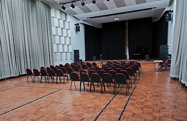 Auditório do centro de treinamento de Jacarta, com palco, tela de projeção e assentos.