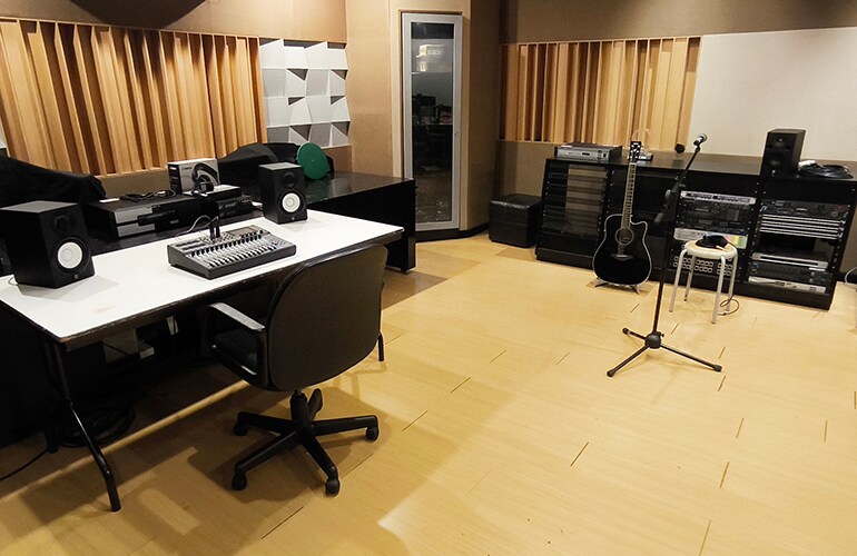 Sala do centro de treinamento de Jacarta, com mesas, assentos e equipamentos de treinamento de áudio.