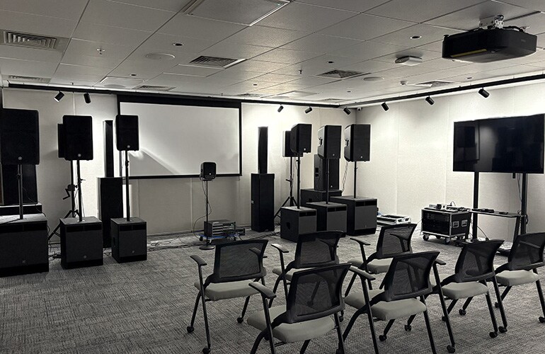 Sala do centro de treinamento de Bengaluru, com tela de apresentação, assentos e equipamentos de áudio.
