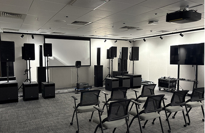 Sala do centro de treinamento de Bengaluru, com tela de apresentação, assentos e equipamentos de áudio.