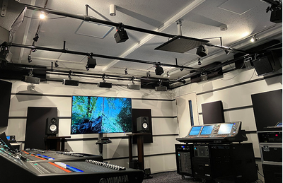 Centro de treinamento de Yokohama, com uma tela grande, consoles de mixagem digital, caixas acústicas e equipamentos de áudio.