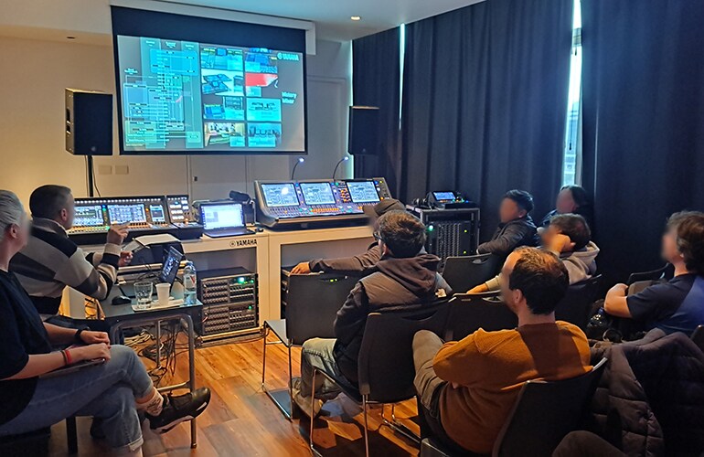 Centro de treinamento de Buenos Aires, com participantes sentados em uma sala de treinamento de áudio equipada com projeção e mixagem.