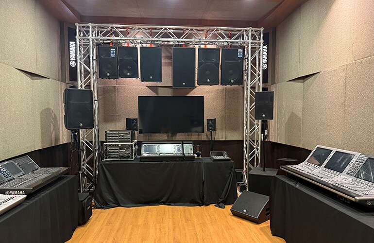 Sala do centro de treinamento de Kuala Lumpur, com área de palco, assentos e equipamentos de áudio.
