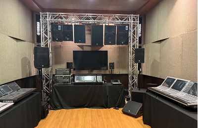 Sala do centro de treinamento de Kuala Lumpur, com área de palco, assentos e equipamentos de áudio.