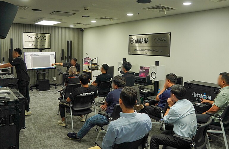 Centro de treinamento da Cidade de Ho Chi Minh, com participantes sentados durante uma sessão de treinamento de áudio.